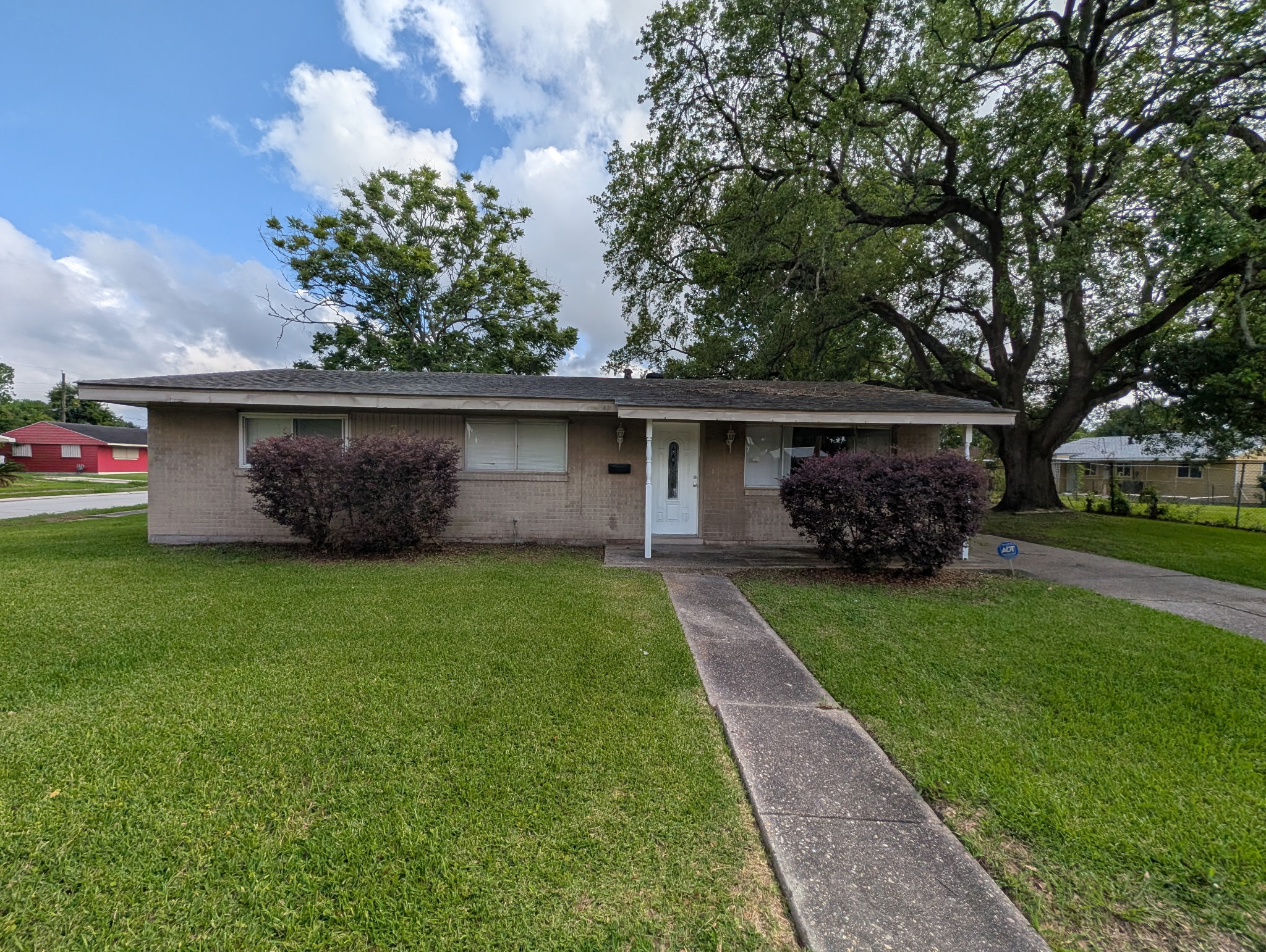 Brick ranch home with a front walkway and mature oak tree
